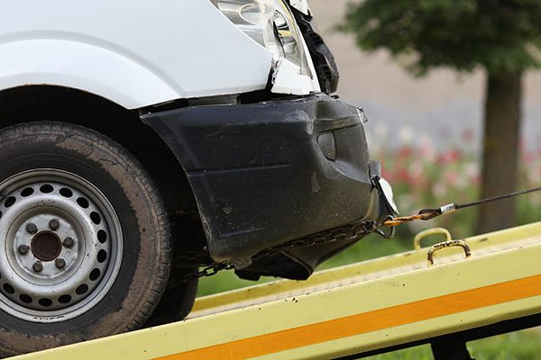 Wrecked car drives into tow truck closeup low insurance offer van