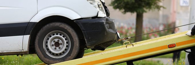 Wrecked car drives into tow truck closeup low insurance offer van