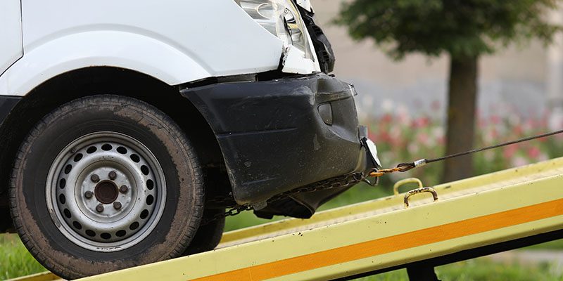 Wrecked car drives into tow truck closeup low insurance offer van
